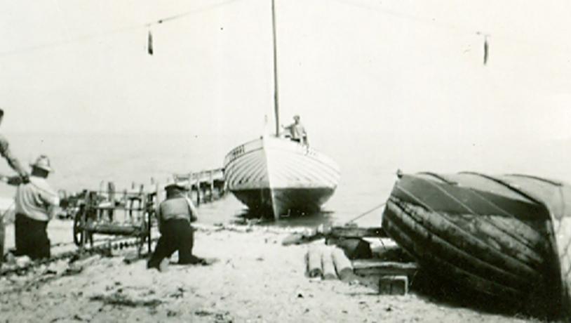 Poul Clausen er ved at få sin store fiskerbåd trukket op på stranden ved Maemosen.